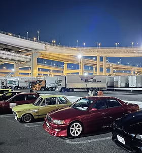 Rangée de voitures japonaises classiques d'un club de tuning garées de nuit sous les rampes autoroutières de Daikoku Futo